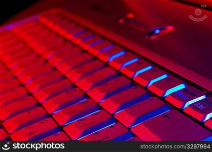 Close-up photo of the keyboard of an open notebook; blue red tone