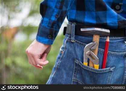 Close up picture of a craftsman with hammer, pencil and gripper in his pocket