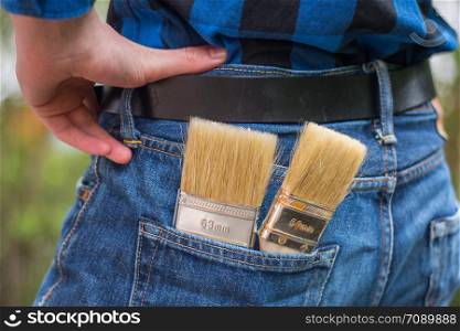 Close up picture of a craftsman with paint brushes in his pocket