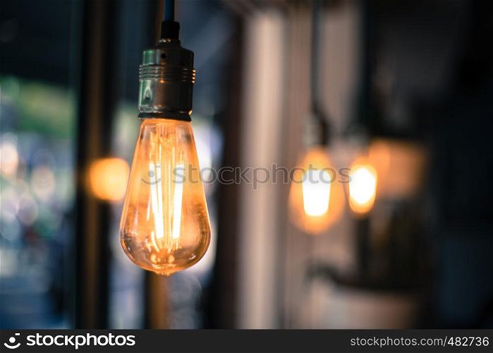 Close up picture of a hanging orange lightbulb in a restaurant or cafe