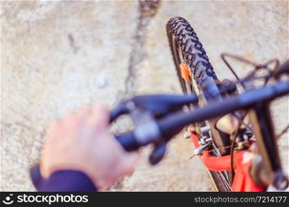 Close up picture of a mountain bike tyre, blurry handlebar, summer day