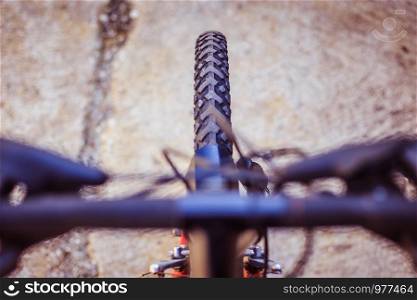 Close up picture of a mountain bike tyre, blurry handlebar, summer day