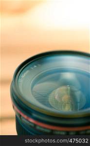 Close up picture of a professional optic photo lens. Smooth blurry background, warm colors.