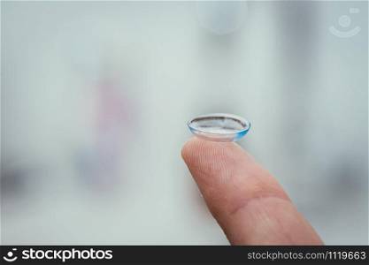 Close up picture of contact lens on a mans finger. Text space.