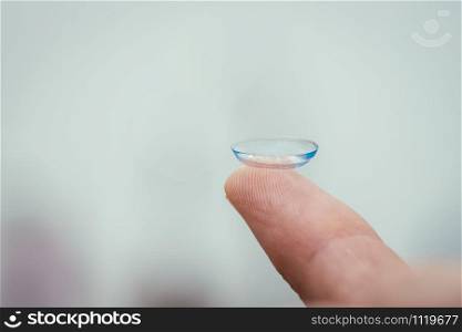 Close up picture of contact lens on a mans finger. Text space.