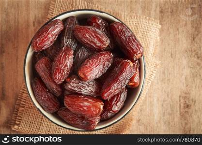 close up picture of dates palm fruit in cup on sackcloth, wooden table background. Dates palm fruit dry is snack healthy.