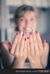 Close up picture of female fingers with colorful nail polish, face in the blurry background