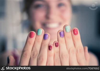 Close up picture of female fingers with colorful nail polish, face in the blurry background