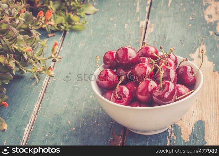Close up picture of fresh red strawberries lying in a white bowl on a rustic table, outdoors