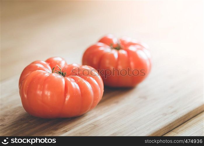 Close up picture of oxheart tomatoes on a bamboo wood plate.
