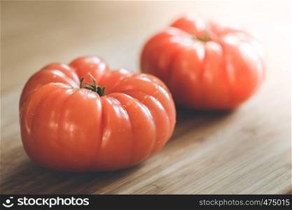 Close up picture of oxheart tomatoes on a bamboo wood plate.