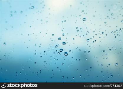 Close up picture of water drops on the window. Blue sky and clouds in the background.
