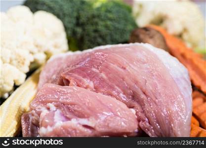 Close up piece fresh raw meat of pork and many vegetables are baby corn, broccoli flowers, mushroom, carrot, cauliflower Ingredients for food preparation cooking. Meat of pork and vegetables for food preparation