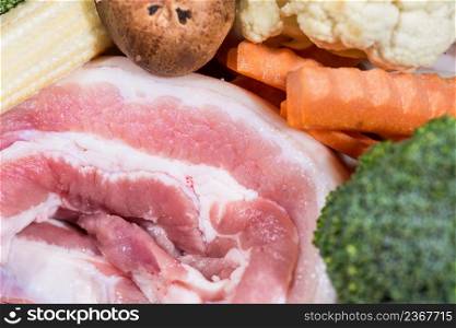 Close up piece fresh raw meat of pork belly and many vegetables are baby corn, broccoli flowers, mushroom, carrot, cauliflower Ingredients for food preparation cooking. Meat of pork belly and vegetables for food preparation