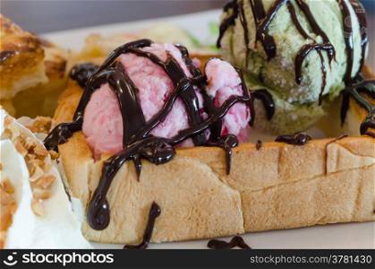 close up pink ice cream with oney toast and whipping cream with chocolate sauce . honey toast and ice cream