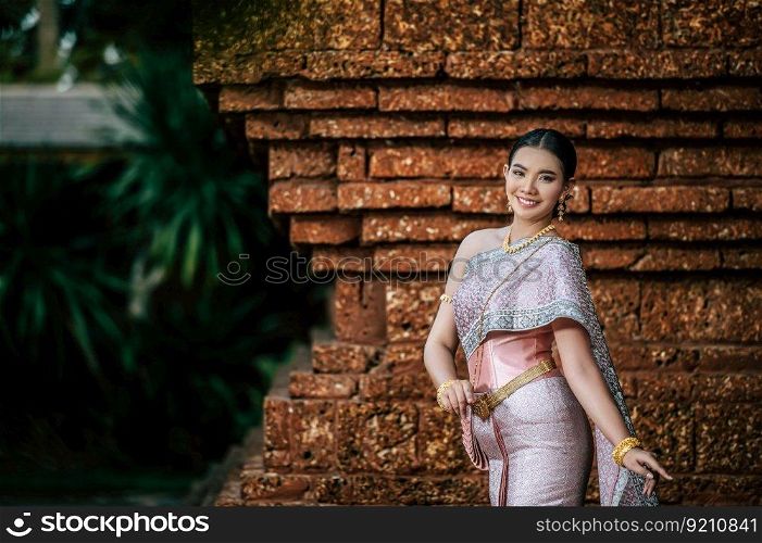Close up, Portrait Asian charming woman wearing beautiful typical Thai dress identity culture of Thailand in ancient temple or famous place with gracefully pose, copy space