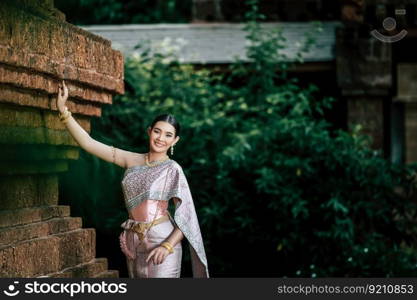 Close up, Portrait Asian charming woman wearing beautiful typical Thai dress identity culture of Thailand in ancient temple or famous place with gracefully pose, copy space