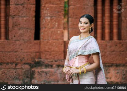 Close up, Portrait Asian charming woman wearing beautiful typical Thai dress identity culture of Thailand in ancient temple or famous place with gracefully pose, copy space