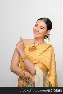 Close up, Portrait beautiful Asian woman in traditional Thai dress costume smile and point her finger with gracefully pose  on white background, copy space