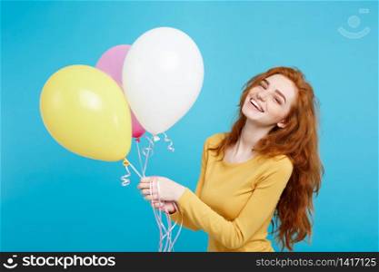 Close up Portrait happy young beautiful attractive redhair girl smiling with colorful party balloon. Blue Pastel Background.. Celebrating Concept - Close up Portrait happy young beautiful attractive redhair girl smiling with colorful party balloon. Blue Pastel Background.