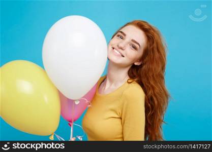 Close up Portrait happy young beautiful attractive redhair girl smiling with colorful party balloon. Blue Pastel Background.