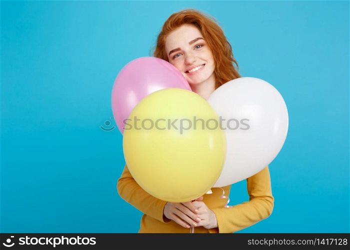 Close up Portrait happy young beautiful attractive redhair girl smiling with colorful party balloon. Blue Pastel Background. Copy space.