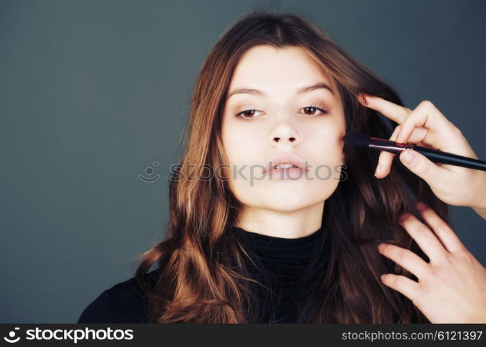 Close-up portrait . In the face of the girl model, make-up artist on the basis of tone is a special brush. Face Care , bb and cc cream. Nude make up