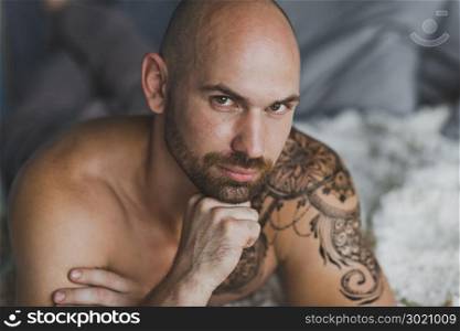Close-up portrait of a bald brutal man with a beard.. Portrait of a man with muscled and tattooed 16.