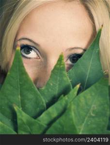 Close-up portrait of a beautifil girl holding leaves in front of face