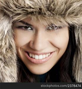 Close-up portrait of a beautiful and happy  young woman wearing a fur hat