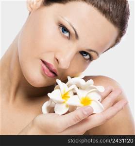 Close up portrait of a beautiful blonde woman holding plumeria flowers close to the face