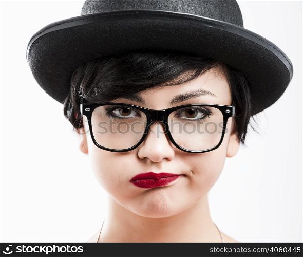 Close-up portrait of a beautiful girl bored with something, wearing a hat and nerd glasses