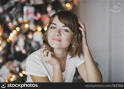 Close-up portrait of a beautiful girl on the background of Christmas lights.. The girl in home clothes on the Christmas lights 7335.