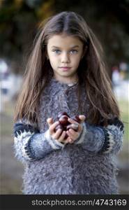 Close up portrait of a Beautiful little girl holding a chestnut in autumn park