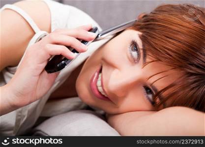 Close-up portrait of a beautiful woman lying on sofa, talking on phone