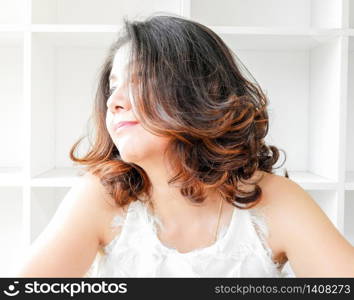 Close up portrait of a beautiful woman smiling, with white bookshelf background.
