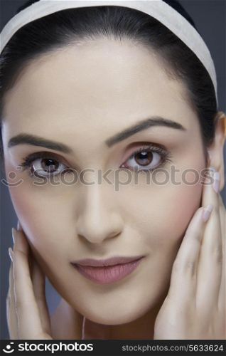 Close-up portrait of a beautiful young woman touching her face