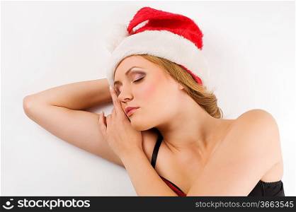 close up portrait of a blond cute girl sleeping with a christmas hat on a white floor