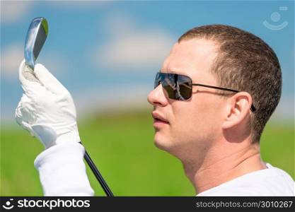 close-up portrait of a golfer looking at his golf club