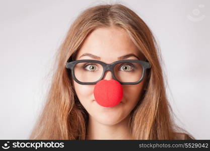 Close-up portrait of a happy 20s girl with red clown nose