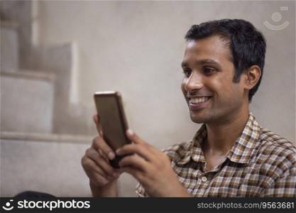 Close-up portrait of a happy young man using mobile phone