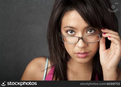 Close up portrait of a pretty brunette woman looking over her glasses