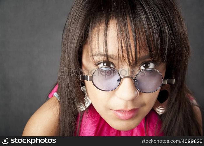 Close up portrait of a pretty brunette woman looking over her glasses