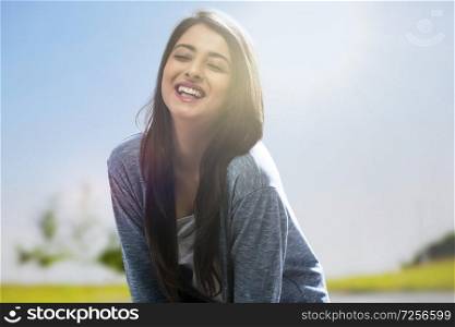 Close up portrait of a smiling teenage girl standing outdoors with her eyes closed