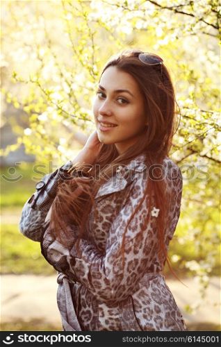 Close up portrait of a trendy woman at sunset standing outdoors in spring landscape background.
