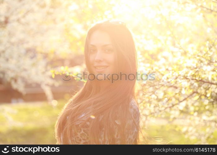 Close up portrait of a trendy woman at sunset standing outdoors in spring landscape background.