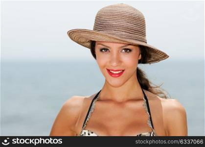 Close up portrait of a woman with a beautiful hat on a tropical beach
