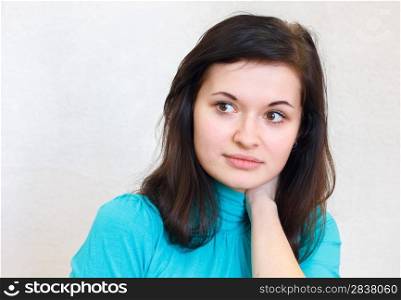 close-up portrait of a young beautiful brunette girl thoughtfully looks aside in the blue sweater