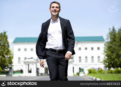 Close up portrait of a young business man in a dark suit and white shirt on the background of summer city