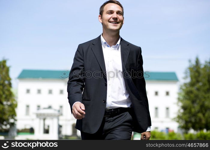 Close up portrait of a young business man in a dark suit and white shirt on the background of summer city